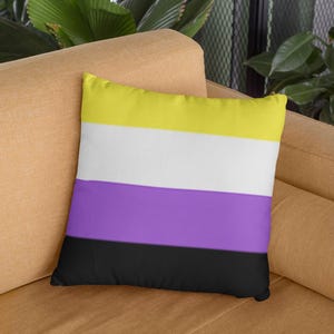 Pode incluir: Uma almofada listrada amarela, branca, roxa e preta. A almofada está em um sofá marrom.
