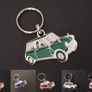 Può includere: Un portachiavi d'argento con un'auto in miniatura verde attaccata. L'auto è una Mini Cooper classica con dettagli argentati e ruote nere.