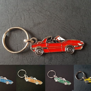 Peut inclure: Un ensemble de cinq porte-clés représentant une voiture rouge, bleue, verte, jaune et orange. Chaque porte-clés est doté d'un anneau argenté et d'un charme en métal représentant une voiture décapotable.