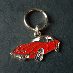 Peut inclure: Un porte-clés en métal rouge en forme de voiture de sport vintage. La voiture a des finitions argentées et un anneau de clé argenté.