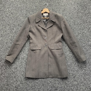 May include: A grey blazer with a notched collar, three buttons, and two front pockets. The long-sleeved jacket is hanging on a wooden hanger.