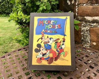 May include: A vintage Mickey Mouse Annual book with a brown cover and a yellow illustration of Mickey Mouse, Pluto, and Donald Duck. The book features the text "Mickey Mouse Annual" in blue and red letters.