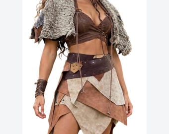 May include: A brown cropped top with lace-up details, a textured gray faux fur shrug, and a layered skirt featuring alternating brown and beige panels with a wide dark brown belt. A matching brown wrist cuff is worn on the right arm.