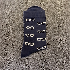 Op de afbeelding: Een paar donkerblauwe sokken met een wit patroon van brillen.