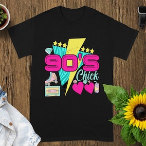 以下が含まれることがあります： カラフルな90年代のグラフィックが施された黒いTシャツ。デザインには「90's Chick」の文字、ローラースケート、カセットテープ、ハート、星、稲妻が含まれています。シャツは柔らかい素材で作られています。