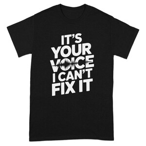 May include: Black t-shirt with white text that reads "IT'S YOUR VOICE I CAN'T FIX IT". The text includes a sound wave graphic. A casual tee for music lovers, sound engineers, or anyone who appreciates a good pun.