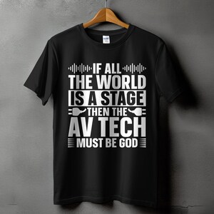 May include: Black t-shirt with the text "IF ALL THE WORLD IS A STAGE THEN THE AV TECH MUST BE GOD" in white. The design includes audio wave graphics and stylized AV equipment symbols.