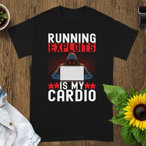Pode incluir: Camiseta preta com o texto "RUNNING EXPLOITS IS MY CARDIO" em branco e vermelho. O gráfico mostra uma figura encapuzada trabalhando em um laptop. Um girassol e uma pequena planta em vaso estão no fundo.