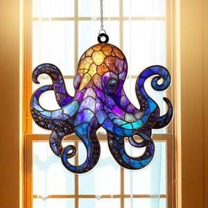 Op de afbeelding: Een glas-in-lood octopus zonnevanger met een ketting om op te hangen. De octopus heeft een mozaïekontwerp met tinten blauw, paars, oranje en geel. De tentakels hebben een wervelend patroon en het stuk wordt voor een raam getoond.