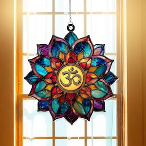 May include: A stained glass lotus flower suncatcher with a central Om symbol. The suncatcher features a vibrant array of colors including blue, purple, red, and yellow. It hangs from a chain, designed for window display.