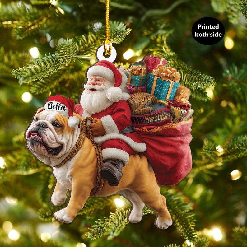 Pu&ograve; includere: Un ornamento natalizio con Babbo Natale su un bulldog. Babbo Natale indossa un abito e un cappello rossi, con la barba bianca. Il bulldog &egrave; marrone e bianco, con un cappello da Babbo Natale con il nome "Bella". Un sacco rosso di regali &egrave; dietro Babbo Natale. Il testo "Printed both side" &egrave; visibile.
