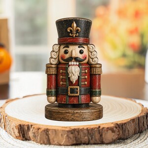 Peut inclure: Une figurine de casse-noisette en bois avec un chapeau noir orné d'un emblème fleur-de-lis doré, une veste rouge à bordure verte, des épaulettes dorées, une ceinture noire à boucle dorée et une barbe blanche sur un socle circulaire en bois.