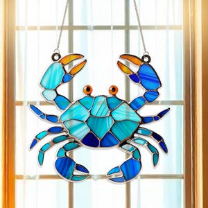 May include: A stained glass blue crab with orange claws hanging from a silver chain. The crab is made of many small pieces of glass in shades of blue, turquoise, and white.