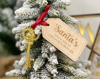 May include: A wooden Christmas ornament with the text "Santa's Magic Key To: Archie's House" and a gold-colored key with a Santa Claus figure on the top.