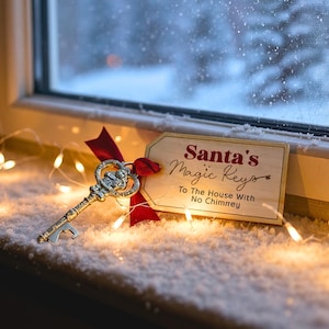 Può includere: Una chiave decorativa argentata con un'etichetta che recita "Santa's Magic Keys To The House With No Chimney" è attaccata con un nastro rosso. La chiave poggia su un davanzale innevato, con luci natalizie e una finestra sullo sfondo.