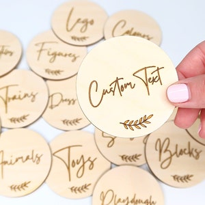 May include: Wooden circle tags with various text, including "Lego", "Figures", "Trains", "Dress", "Animals", "Toys", "Blocks", "Playdough", and "Custom Text".