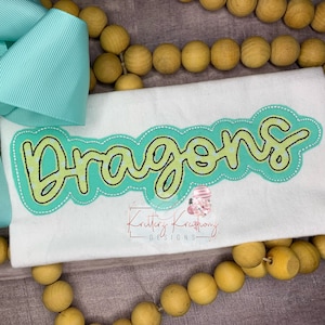 May include: A white t-shirt with a green and yellow embroidered design that says "Dragons".