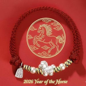 May include: Red braided bracelet with a silver horse charm, pearls, and a small tag. The bracelet is set against a red background with a gold horse illustration. Text at the bottom reads "2026 Year of the Horse."