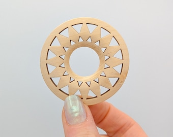 May include: A wooden circle with a geometric design of triangles cut out. The circle is light brown and has a hole in the center.