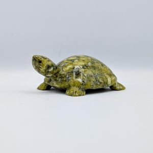 May include: A small, green and white marble turtle figurine. The turtle is carved in a realistic style and has a detailed shell.