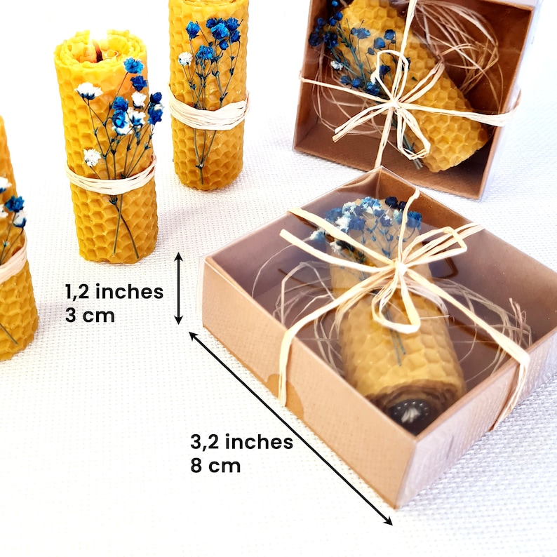 May include: Three small, yellow beeswax candles with dried blue and white flowers, packaged in a clear box with a brown lid. The candles are 1.2 inches tall and the box is 3.2 inches wide.