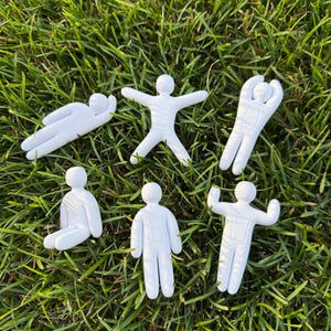 May include: Six white plastic stick figures in various poses, including lying down, jumping, reaching upward, sitting, standing, and flexing arms. Each figure features a smooth, rounded design with subtle molded details on the torso and head.