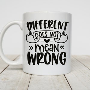 May include: White ceramic coffee mug with a black inscription that reads "Different does not mean wrong".