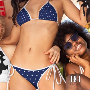 May include: A navy blue bikini with a white polka dot pattern and white trim. The top features a triangle design with thin straps, and the bottom includes side ties. The logo RH Rebel Honey is visible in the bottom right corner of the image.