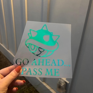 May include: A turquoise green sticker with a cartoon image of a spiky, shelled creature with the text "GO AHEAD... PASS ME" underneath.