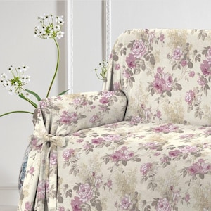 Puede incluir: Una funda de sof&aacute; floral con fondo crema y rosas rosas. La funda tiene un lazo en la parte delantera y est&aacute; hecha de un tejido suave y texturizado.