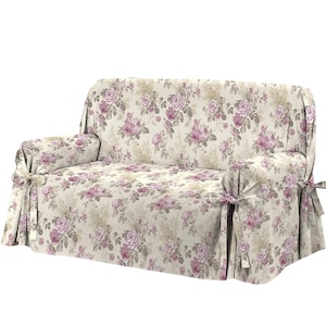 Puede incluir: Una funda de sof&aacute; floral con fondo beige y rosas rosas. La funda tiene una falda fruncida y lazos en las esquinas.