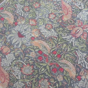 May include: A vintage fabric with a repeating pattern of stylized birds, flowers, and leaves. The fabric is a dark gray background with shades of pink, red, green, and yellow.