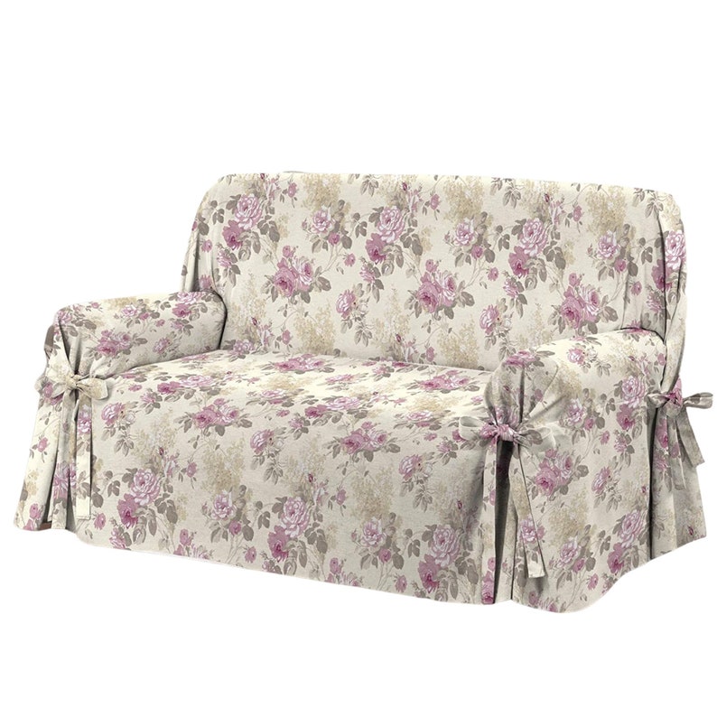 Puede incluir: Una funda de sof&aacute; floral con fondo beige y rosas rosas. La funda tiene una falda fruncida y lazos en las esquinas.