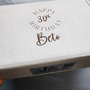 May include: A white gift box with a brown inscription that reads "Happy 30th Birthday Beto".