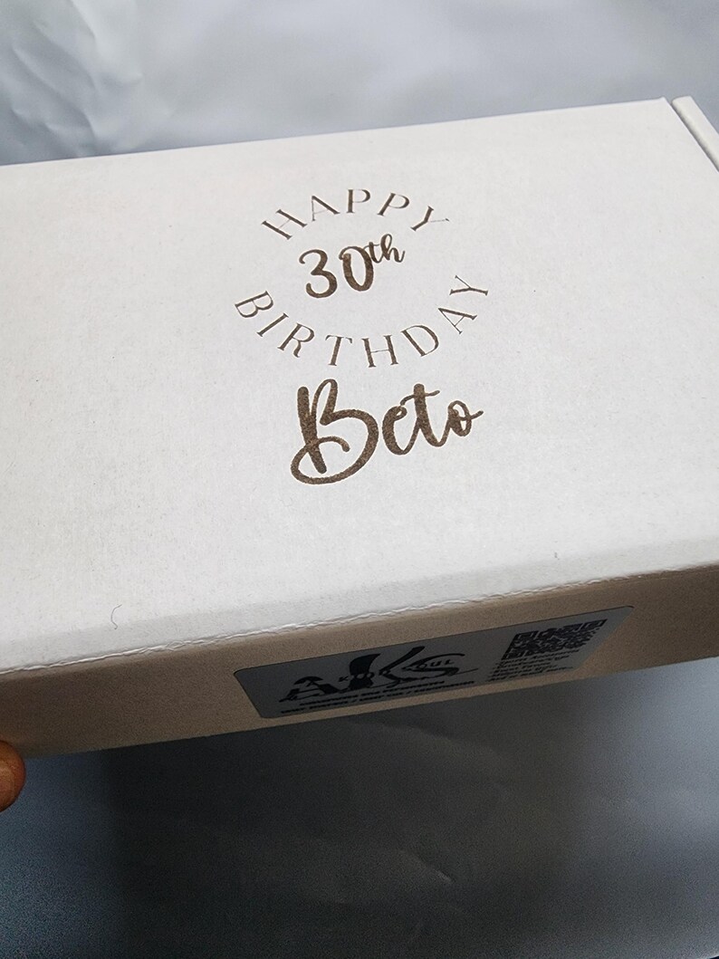 May include: A white gift box with a brown inscription that reads "Happy 30th Birthday Beto".