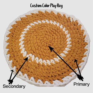 May include: A round, custom color play rug with a white border and a spiral pattern. The primary color is a light brown and the secondary color is white.