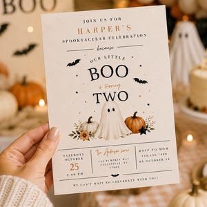 May include: A rectangular invitation card with a cream background featuring a central ghost illustration, pumpkins, and bats. The text reads: Join us for Harper's spooktacular celebration because our little BOO is turning TWO, with event details.