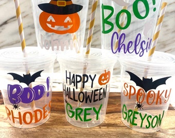 May include: Five clear plastic Halloween-themed cups with lids and striped straws. Each cup features a different design: a pumpkin with a witch hat, a ghost, the word "Boo!" with a bat, and the phrases "Happy Halloween" and "Spooky".