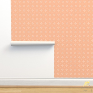 May include: A roll of peach-colored wallpaper with a white repeating pattern of small geometric shapes. The wallpaper is partially unrolled, revealing the white wall behind it.