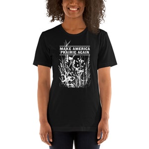 May include: Black t-shirt with a white graphic of tall grass and the text "Make America Prairie Again."