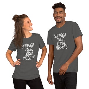 Puede incluir: Dos personas con camisetas grises antracita con el texto "Support Your Local Insects" impreso en blanco.