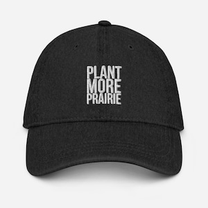 Może przedstawiać: Czarna czapka z daszkiem z białym haftem z napisem "PLANT MORE PRAIRIE".