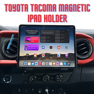 May include: A black dashboard with a red trim in a Toyota Tacoma truck. A magnetic iPad holder is attached to the air vent and an iPad is mounted in the holder. The iPad screen shows a variety of apps, including the Apple Music app.