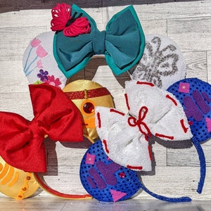 May include: A set of six colorful Disney-themed Minnie Mouse ears. The ears are made of fabric, sequins, and other decorative materials. The ears are in various colors, including red, white, blue, green, and purple.