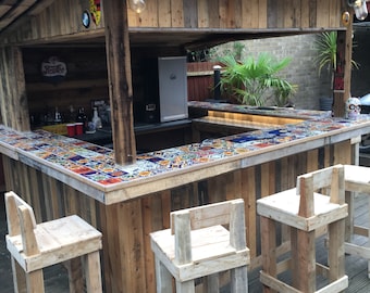 May include: A wooden bar with a tiled countertop and three wooden stools. The bar is made from reclaimed wood and has a rustic look. The stools are also made from reclaimed wood and have a simple design.
