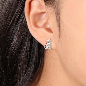 May include: Silver cat stud earrings. The earrings are small and feature a detailed cat design.