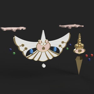 Op de afbeelding: Een wit en gouden ornament in de vorm van een vlinder met een roze centrum en blauwe ogen. Het ornament is omringd door kleine, kleurrijke stippen. Er is ook een gouden, puntig ornament met een roze top en een kroon.