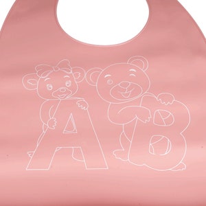 May include: Pink silicone baby bib with a white outline of a bear holding the letter B and a bear with a bow holding the letter A.