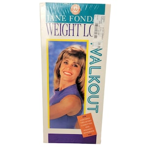 May include: A sealed VHS tape of Jane Fonda's "Weight Loss Walkout." The box features a photo of Jane Fonda in a blue top, with the words "Weight Loss Walkout" and "Valkout" printed on the box. The box also states that it contains two audio cassettes and a walkout handbook.