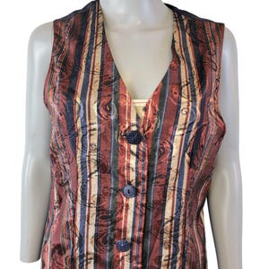 May include: A sleeveless vest with a striped and floral pattern in shades of red, blue, and gold. The vest has a V-neck and button closure.
